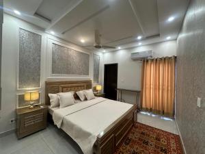 a bedroom with a large bed and two windows at Premium 2 bed room apartment in Lahore