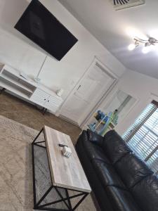 a living room with a leather couch and a table at Charming Condo - Pool, Minutes to Beach in Pompano Beach