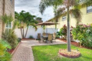 a patio with a table and chairs and a palm tree at Charming Condo - Pool, Minutes to Beach in Pompano Beach