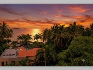 a sunset over a beach with palm trees and the ocean at Tu refugio ideal cerca al mar in Playa Bello Horizonte