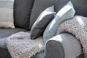 a gray couch with pillows and a blanket on it at Haus Amrumblick in Hedehusum +25 photos