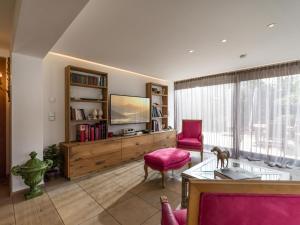 a living room with a tv and pink chairs at Garten Suite mit 2 separaten Studios in Kirchberg in Tirol +13 photos