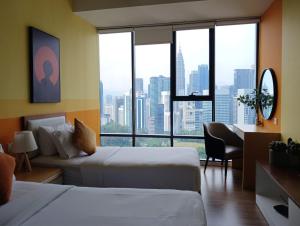 a hotel room with two beds and a desk and a window at Ceylonz Suites By ANA MALAYSIA in Kuala Lumpur