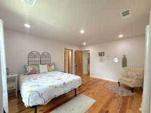 a white bedroom with a bed and a chair at -NEW- Spring Wish - Historical Loop Home- in Eureka Springs