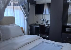 a bedroom with a bed and a desk and a window at Kaa Highway Hotel in Mukono