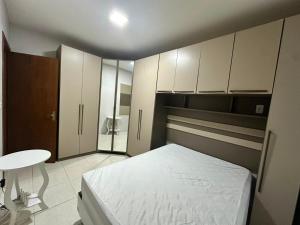 a bedroom with a bed and a table and cabinets at Apartamento Unisc in Santa Cruz do Sul