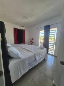a bedroom with a white bed and two windows at OMY Apartments Nagua 2A in Nagua