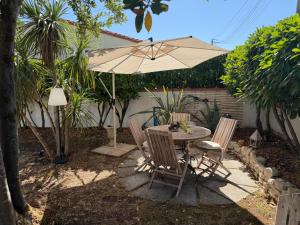 a table and chairs with an umbrella in a backyard at Tredd in La Rochelle