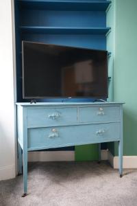 a blue dresser with a tv on top of it at Homesly Guest Rooms, Comfortable En-suite Guest Rooms with Free Parking and Self Check-in in Berwick-Upon-Tweed
