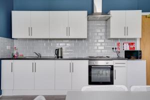 a white kitchen with white cabinets and appliances at Homesly Guest Rooms, Comfortable En-suite Guest Rooms with Free Parking and Self Check-in in Berwick-Upon-Tweed