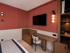 a room with a desk and a tv on a wall at 336 Saint-Honore By Chapitre Collection in Paris