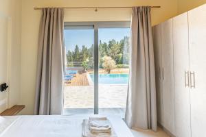 a bedroom with a bed and a sliding glass door at Tsoutsis Villas in Marantochori
