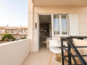 a balcony with a table and a white chair at AVENA Suites in Kato Gouves