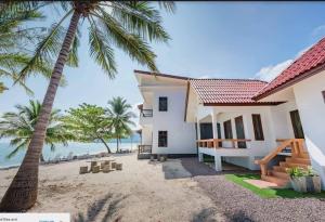 a house on the beach with a palm tree at The Boutique Khanom in Khanom