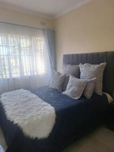 a bed with a blue comforter with pillows and a window at The Cave at 55 St Patricks in Harare