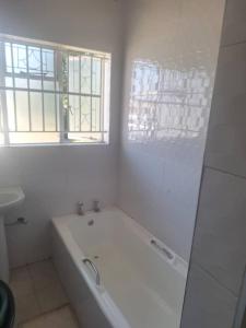 a white bathroom with a tub and a window at The Cave at 55 St Patricks in Harare