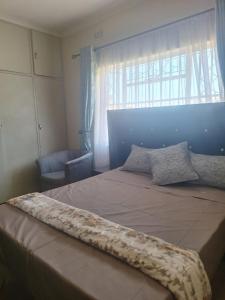 a bedroom with a large bed with a window at The Cave at 55 St Patricks in Harare