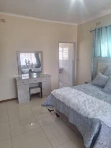 a bedroom with a bed and a desk and a mirror at The Cave at 55 St Patricks in Harare +4 photos