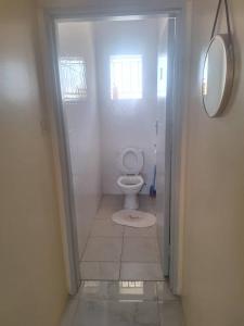 a white bathroom with a toilet and a mirror at The Cave at 55 St Patricks in Harare