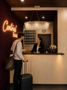 a woman standing at a counter in a hotel with her luggage at Hotel Central Nürnberg Hauptbahnhof in Nuremberg