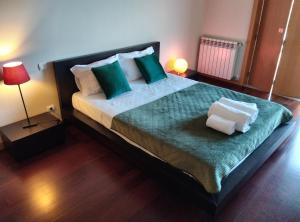 a bedroom with a large bed with green and white pillows at Single House in Vila Real