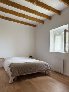 a bedroom with a bed in a white room with wooden ceilings at Maison de Campagne 