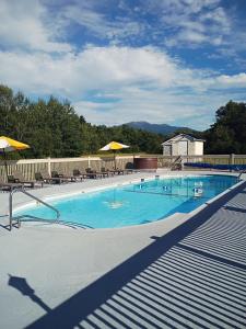 a large blue swimming pool with chairs and umbrellas at Gale River House - Boutique Hotel in Franconia