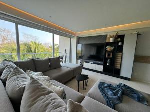 a living room with a couch and a television at Departamento Brisa del Mar Punta Mita, Beach Front in Bucerías