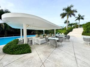 a patio with tables and chairs and a white umbrella at Departamento Brisa del Mar Punta Mita, Beach Front in Bucerías