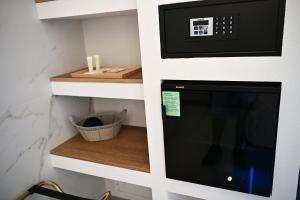a kitchen with a microwave oven and a shelf at Kleos Luxury Rooms in Porto Empedocle