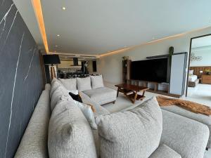 a living room with a large couch and a tv at Departamento Playa Dorada Punta Mita, Beach Front in Punta Mita