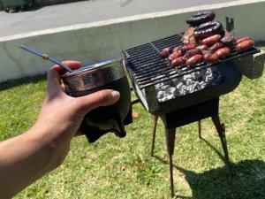 a person is holding a cup of food next to a grill at Valença Guesthouse in Valença