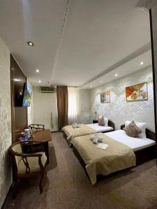 a hotel room with two beds and a desk at Nur m hotel Free transfe hotel in airoport in Yakkasaray