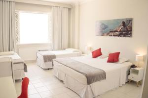 a white room with two beds and a window at CLH Suites Domingos Ferreira in Rio de Janeiro