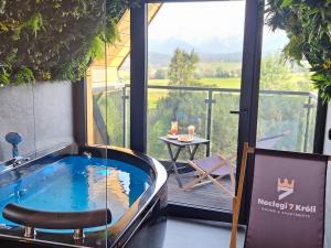 a jacuzzi tub in a room with a balcony at Siedmiu Króli Rooms&SPA in Bukowina Tatrzańska