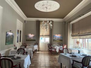 a restaurant with white tables and chairs and a chandelier at Hôtel Chandouineau in Redon