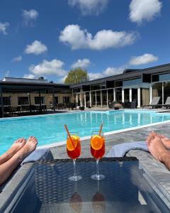 two cocktails sitting on a table in front of a swimming pool at Hotel Balka Strand in Neksø