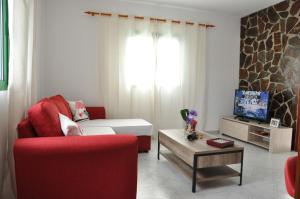 salon z czerwoną kanapą i telewizorem w obiekcie La Casita de Mari Carmen w mieście Mala