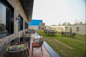 a patio with chairs and tables and a lawn at The ELET near Amritsar Airport in Amritsar