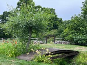 a wooden bridge with a tree in a garden at Ruhnu Bullers-Gita talu in Ruhnu