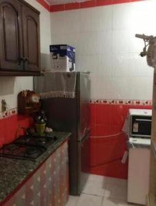 a kitchen with red and white walls and a refrigerator at Superbé appartement bien équipé, situé à environ 300 Mètres de la plage Martil in Martil