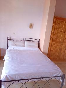 a bedroom with a bed with white sheets and a wooden door at Corfu sunrise sea view apartments 100m from the beach in Benitses