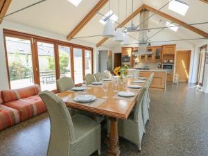 a kitchen and dining room with a wooden table and chairs at Clynnog House in Dwyran