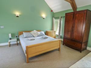 a bedroom with a bed and a wooden cabinet at Clynnog House in Dwyran