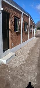 a brick building with two windows and a door at lo de la Gri in El Volcán