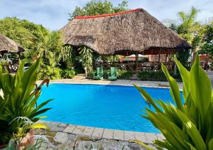 a resort with a swimming pool and a thatch roof at Ngandu Hotel - Rundu in Rundu