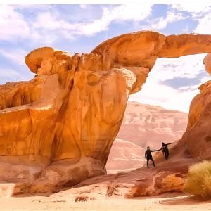two people walking through an arch in the desert at Wadi rum bubble camp in Wadi Musa