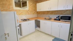 Eine Küche mit weißen Schränken, Spüle und Mikrowelle in der Unterkunft الحاتمية للشقق المخدومة - إقتصادي - Alhatimia For Serviced Apartments - Economy in Abha