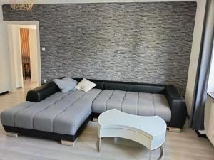 eine schwarze Couch in einem Wohnzimmer mit einer Ziegelwand in der Unterkunft Welschbach in Illingen