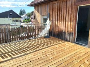 eine Holzterrasse mit weißem Geländer an einem Haus in der Unterkunft Welschbach in Illingen